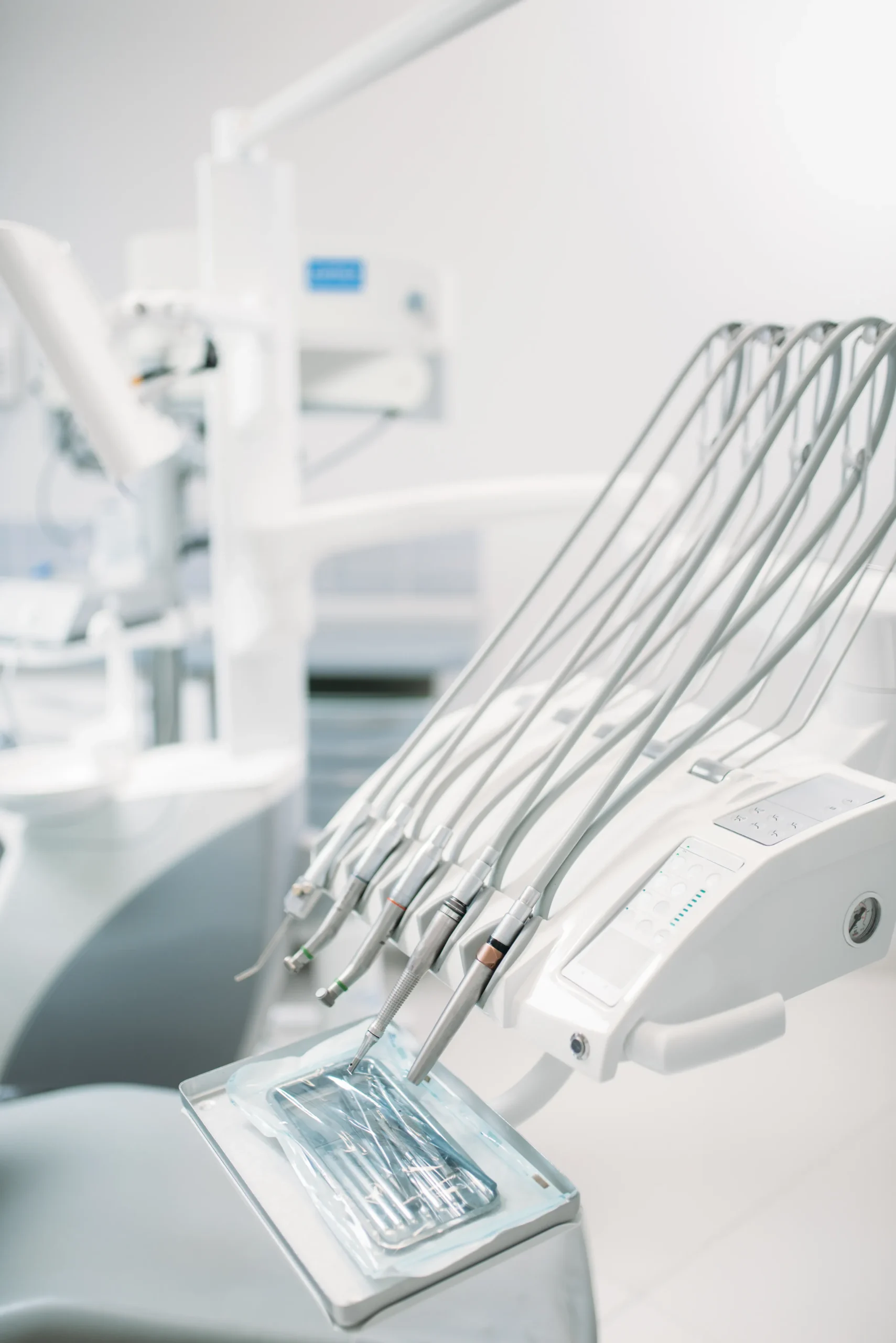 Consola de instrumentos odontológicos con mangueras colibrí, piezas de mano y bandeja metálica esterilizada junto al sillón de tratamiento en la clínica Dentelier en Alicante.