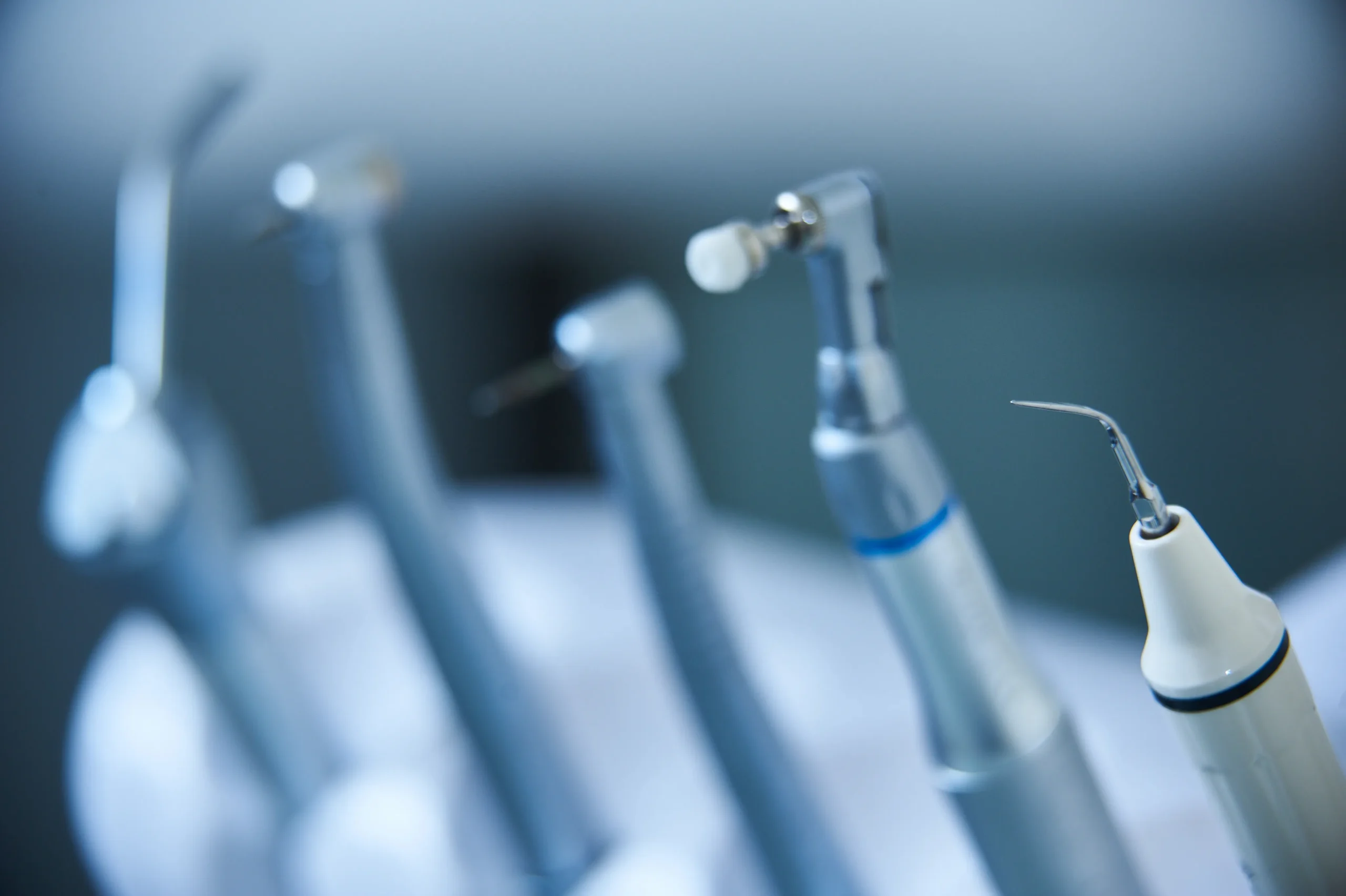 Primer plano de diverso instrumental odontológico de alta tecnología, incluyendo turbinas, contra-ángulos con cepillo de pulido y un raspador ultrasónico en la clínica Dentelier en Alicante.